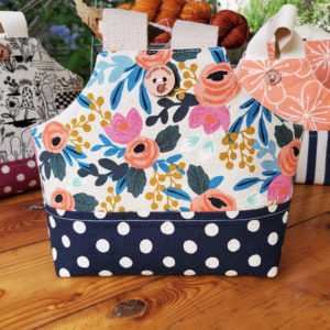 io tote in a floral color print with a navy polka dot base