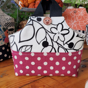 io tote with a black and white floral upper and a raspberry polka dot base